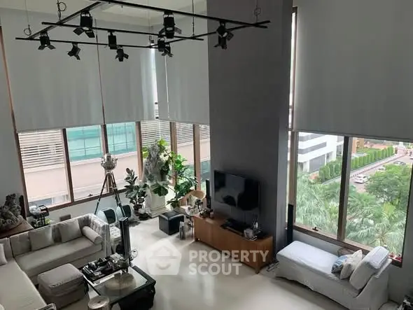 Luxurious high-ceiling living room with large windows and modern decor