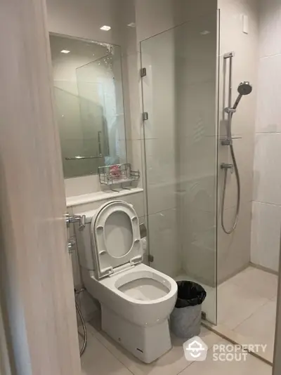 Modern bathroom with glass shower and sleek fixtures in contemporary apartment.