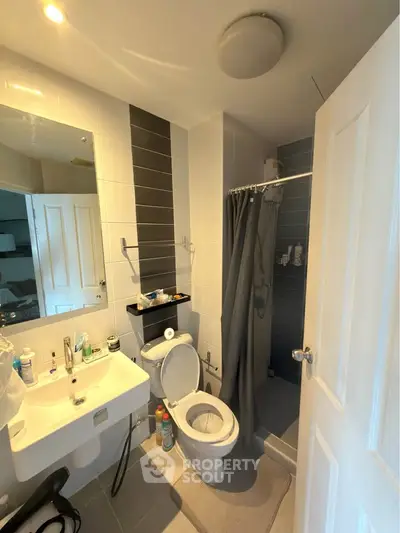 Modern bathroom with shower, toilet, and sink in a stylish apartment.