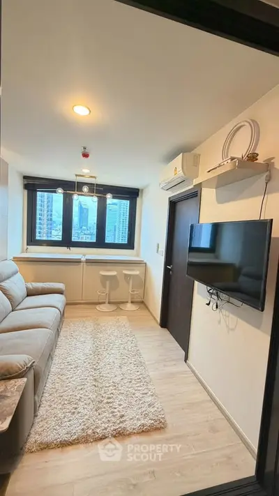 Cozy living room with city view, modern sofa, wall-mounted TV, and stylish decor.