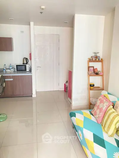 Cozy living room with colorful sofa and modern kitchenette in open layout apartment.
