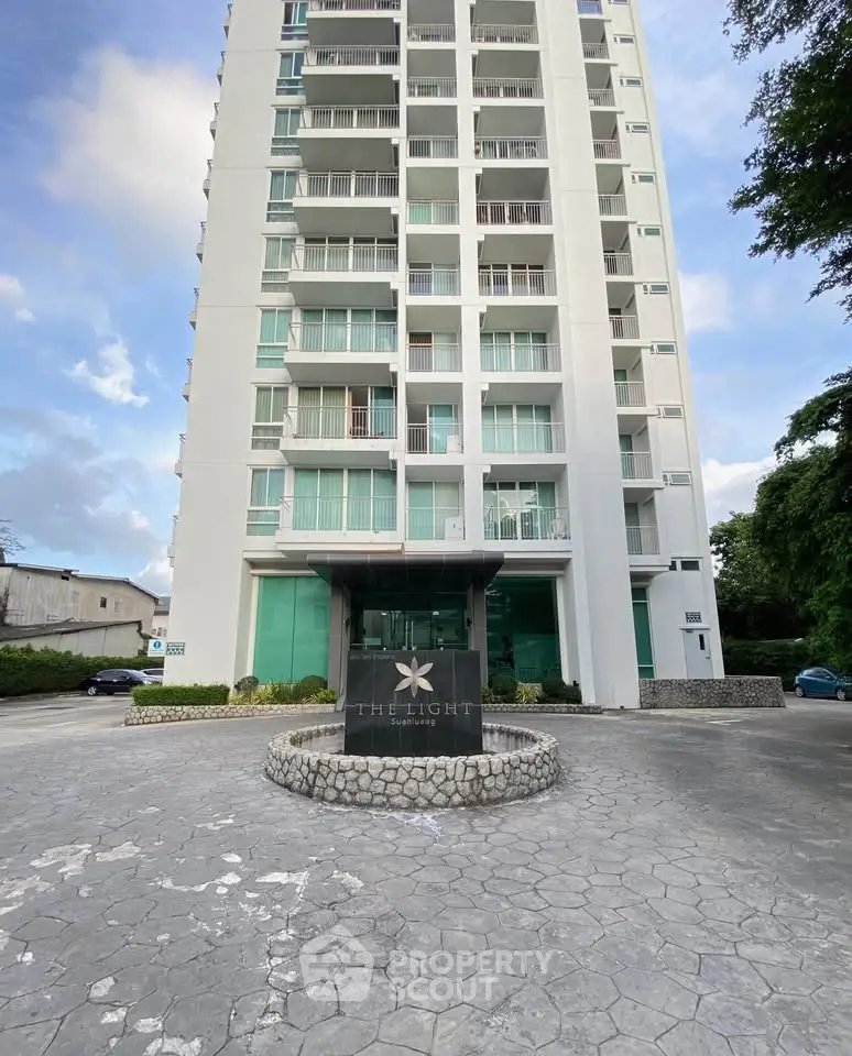 Modern high-rise building exterior with elegant entrance and spacious parking area.