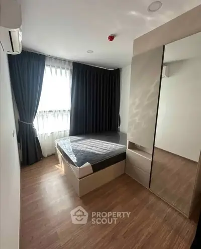 Modern bedroom with sleek design, large window, and mirrored wardrobe.