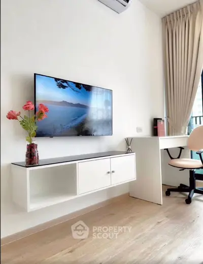 Modern living room with wall-mounted TV, sleek desk, and elegant decor in a bright apartment.