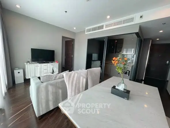 Modern living room with sleek furniture and open kitchen layout in a stylish apartment.