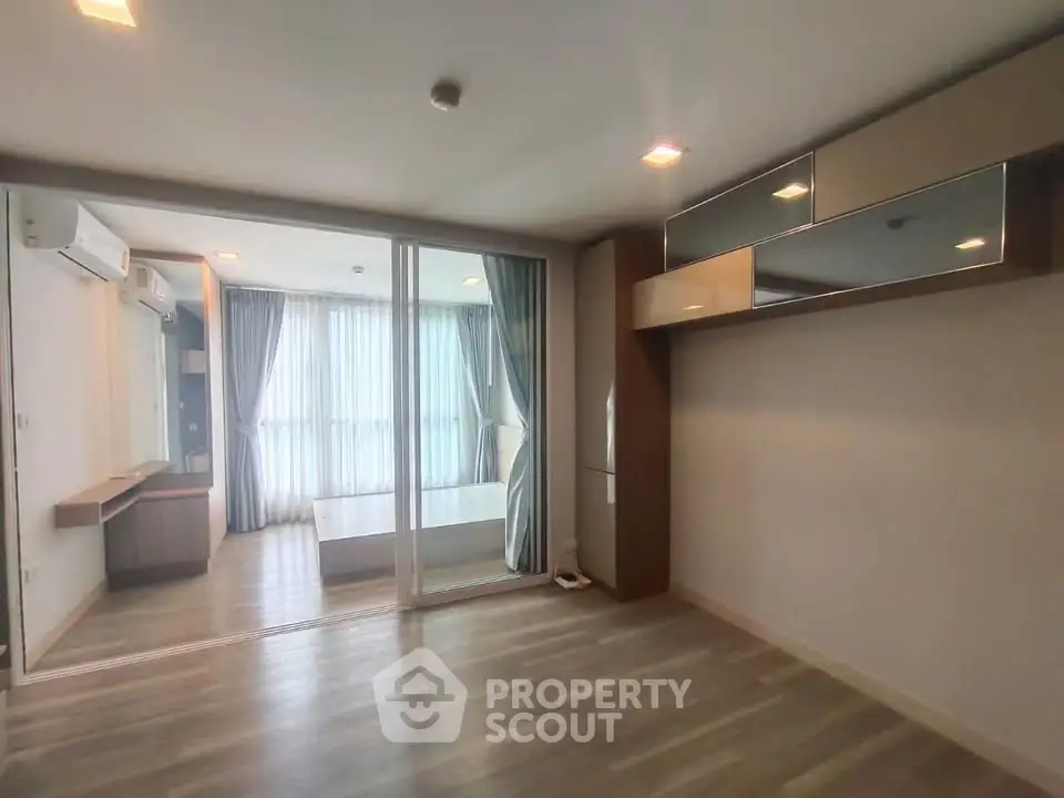 Spacious modern apartment with large windows and sleek wooden flooring, featuring a separate bedroom area.