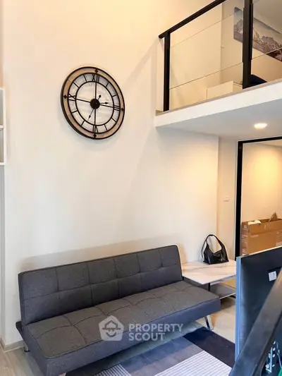 Modern loft-style living room with sleek gray sofa and stylish wall clock, perfect for urban living.