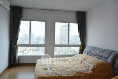 Spacious bedroom with panoramic city view and large windows in modern apartment.