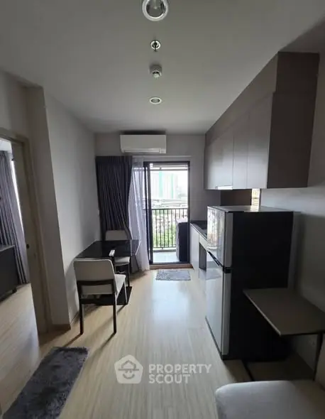 Modern apartment interior with compact kitchen and dining area, featuring sleek design and balcony access.