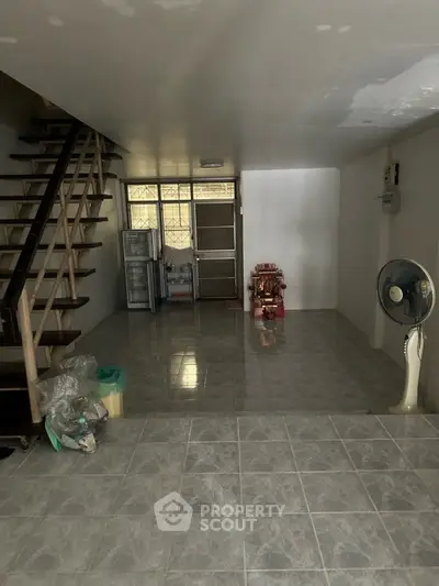 Spacious open-plan living area with staircase and tiled flooring, ideal for customization.