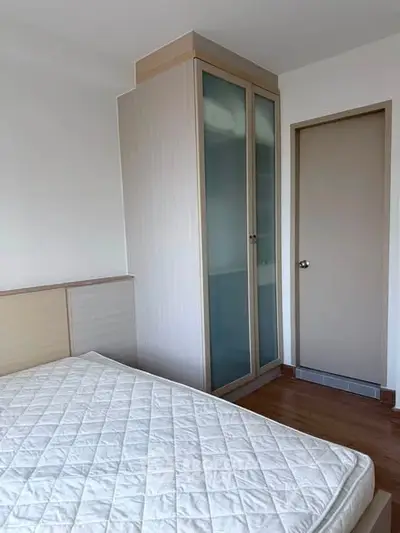 Modern bedroom with minimalist design featuring a built-in wardrobe and wooden flooring.