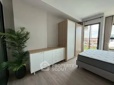 Spacious bedroom with modern furniture and large window offering natural light.