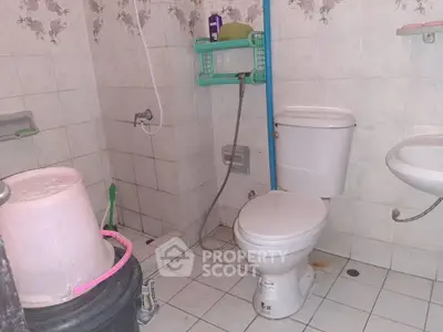 Functional bathroom with essential fixtures and tiled walls, ideal for practical living.
