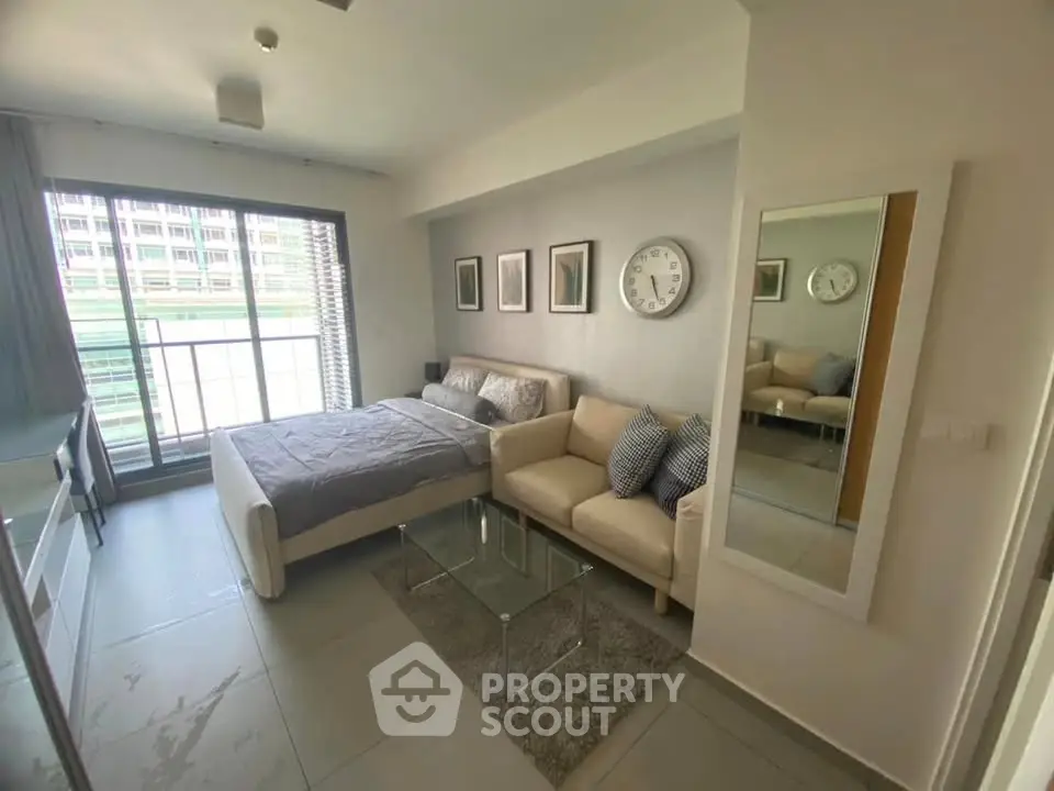 Modern studio apartment with cozy living area and large window view.