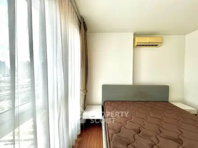 Bright bedroom with large windows and modern air conditioning unit, offering a cozy and inviting atmosphere.