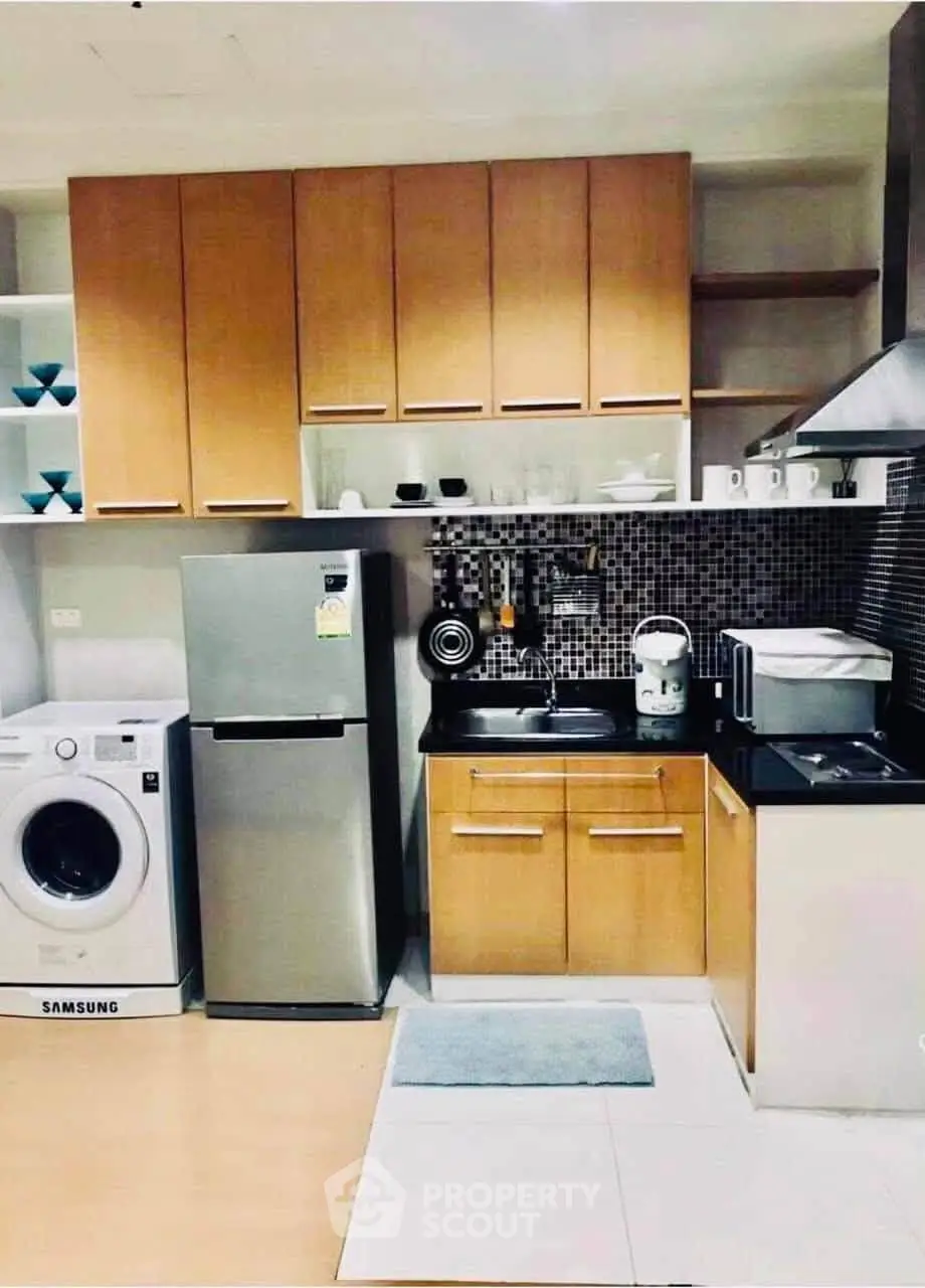 Modern kitchen with wooden cabinets, stainless steel fridge, and washing machine.