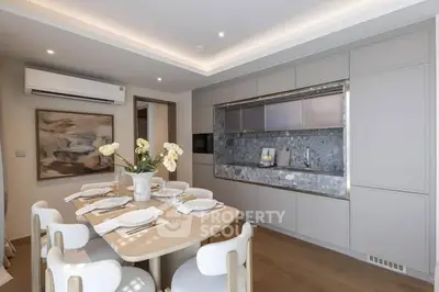 Modern dining area with elegant table setting and built-in kitchen appliances in a stylish open layout.
