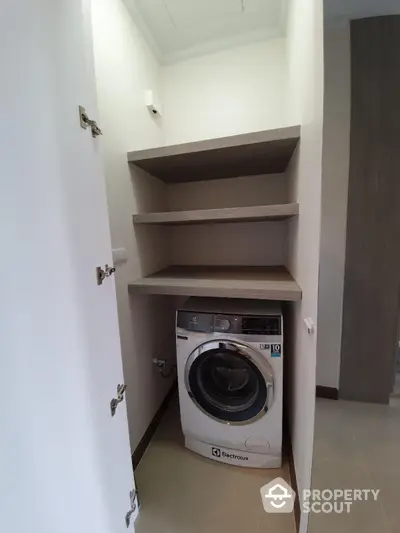 Compact laundry area with modern Electrolux washing machine and built-in shelves