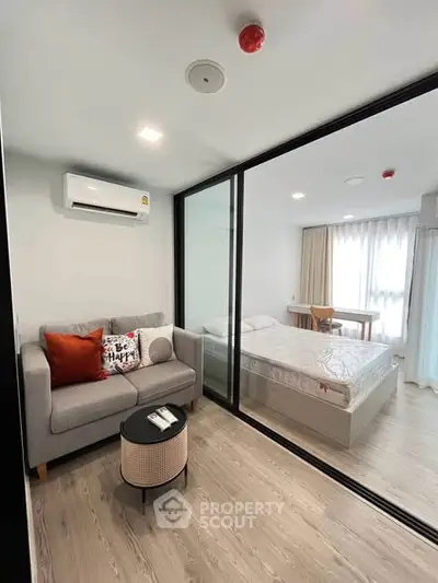 Modern studio apartment with glass partition, cozy living area, and stylish bedroom.