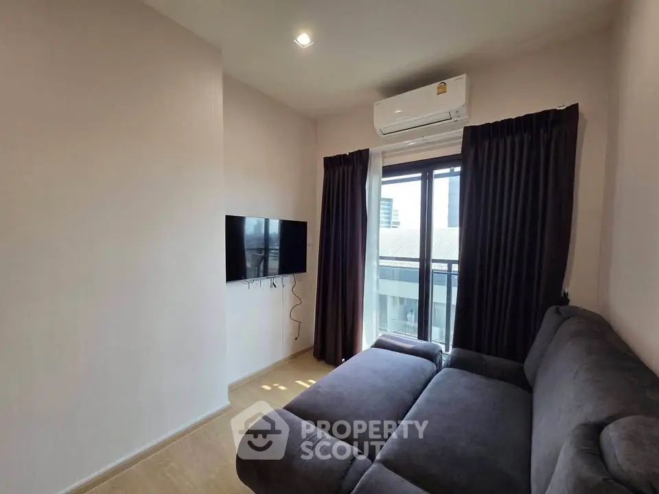 Cozy living room with modern sofa, wall-mounted TV, and air conditioning, featuring a large window with city view.