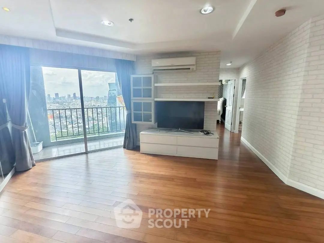 Spacious living room with city view and modern decor in high-rise apartment.