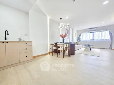 Spacious modern living room with open layout and elegant dining area, featuring stylish furniture and ample natural light.