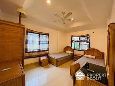 Spacious twin bedroom with natural light and elegant wooden furniture.