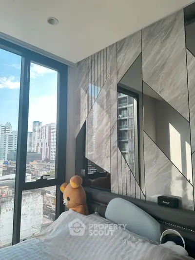 Modern bedroom with large windows and city view, featuring stylish wall design and plush decor.