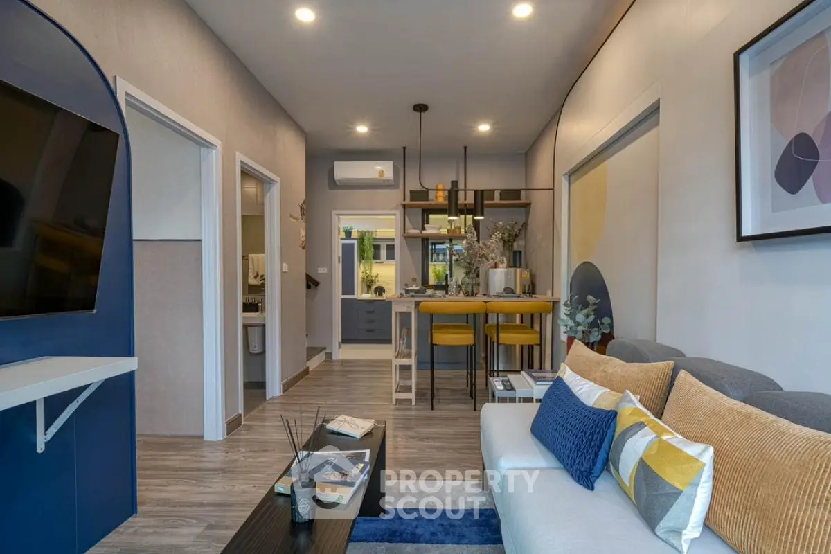 Modern living room with stylish decor and open kitchen layout, featuring cozy seating and contemporary design.