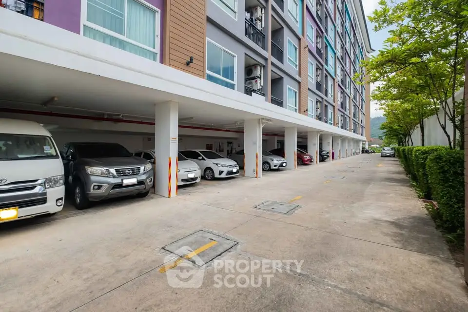 Modern apartment building with spacious parking area and lush greenery.