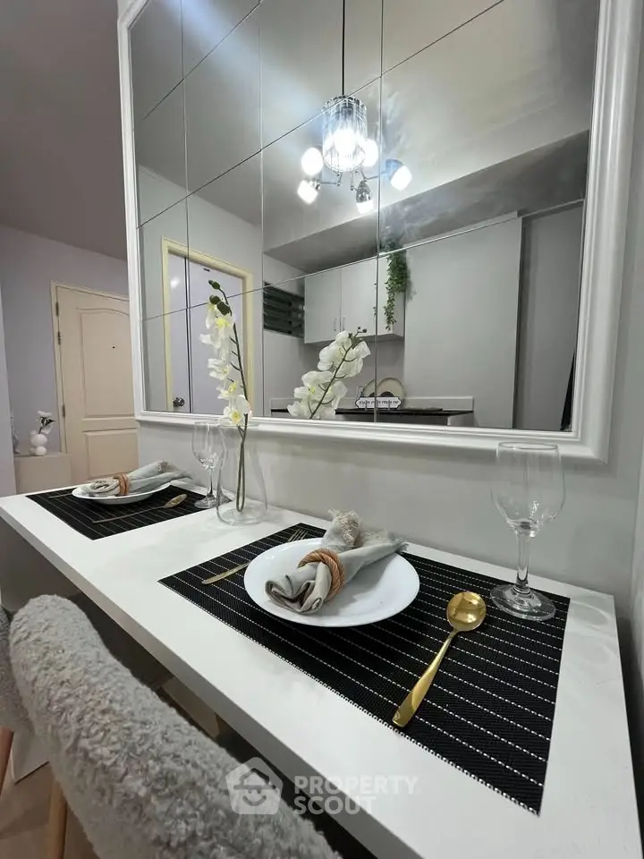 Modern dining area with elegant table setting and mirrored wall in stylish apartment.
