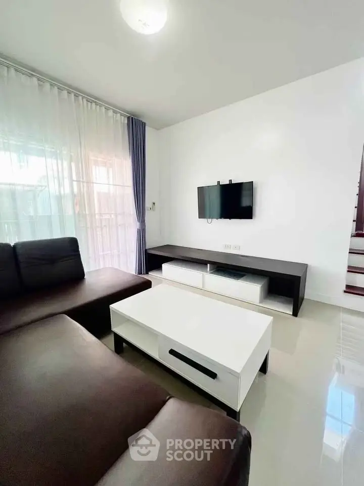 Modern living room with sleek furniture and wall-mounted TV, featuring a cozy ambiance and natural light.