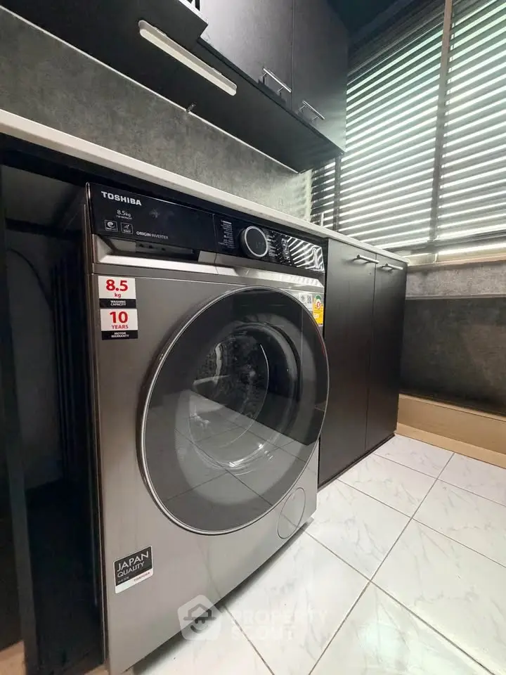Modern laundry area with high-efficiency washing machine and sleek cabinetry.