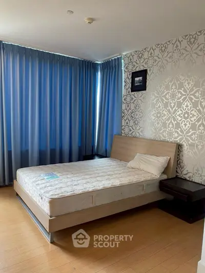 Spacious bedroom with elegant wallpaper and large windows for natural light.