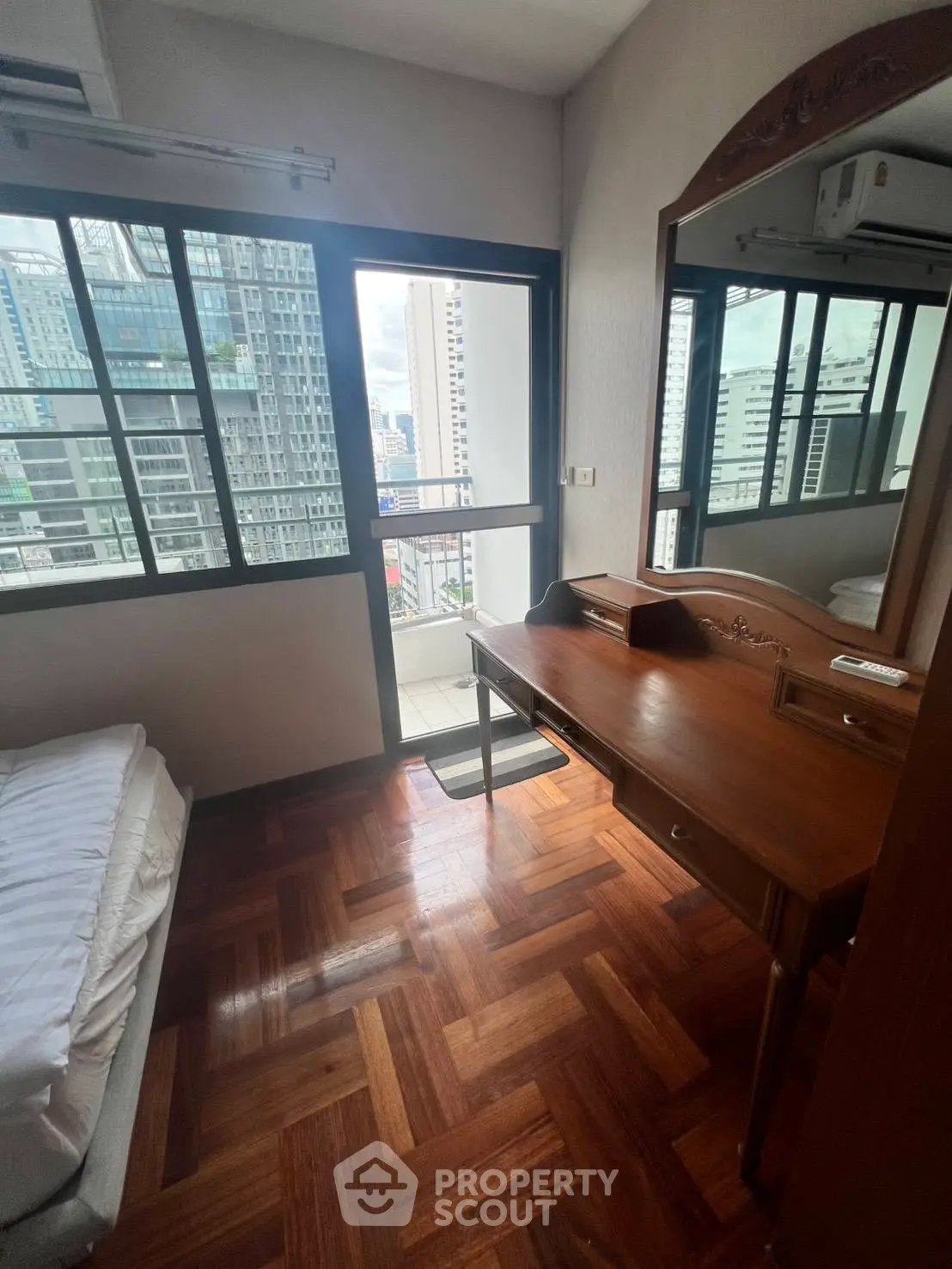 Cozy bedroom with wooden flooring and city view balcony access in modern apartment