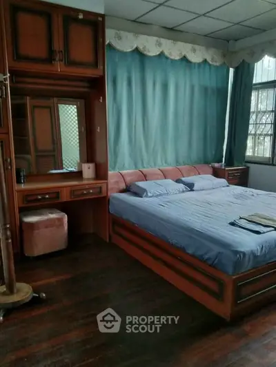 Spacious bedroom with wooden furniture and large windows for natural light.