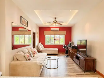 Spacious living room with modern decor, large windows, and ceiling fan, perfect for relaxation and entertainment.