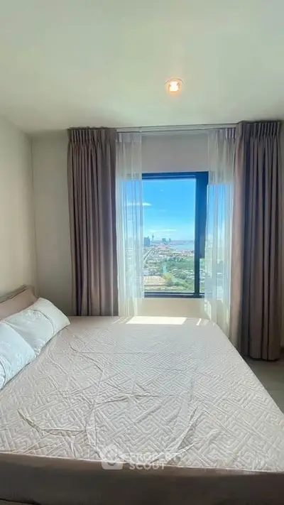 Cozy bedroom with large window offering stunning city views, perfect for relaxation.