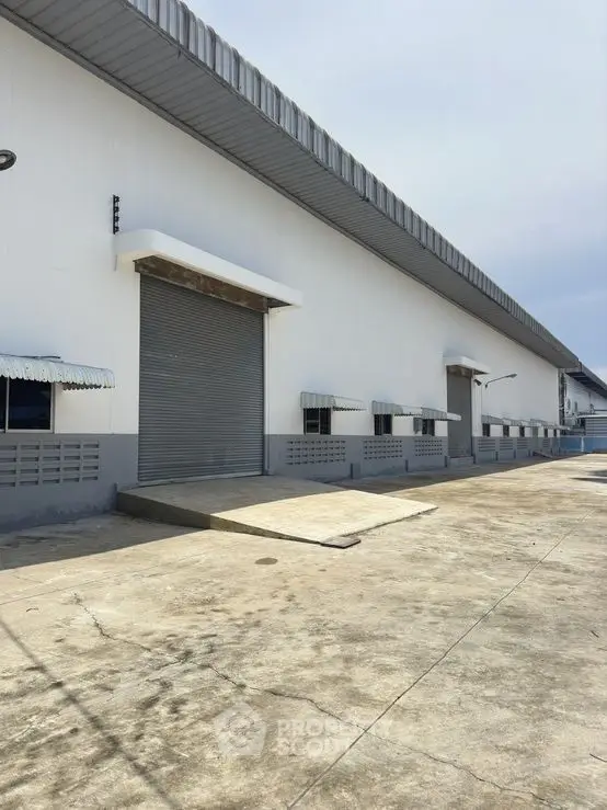 Spacious industrial warehouse exterior with loading docks and ample parking space.