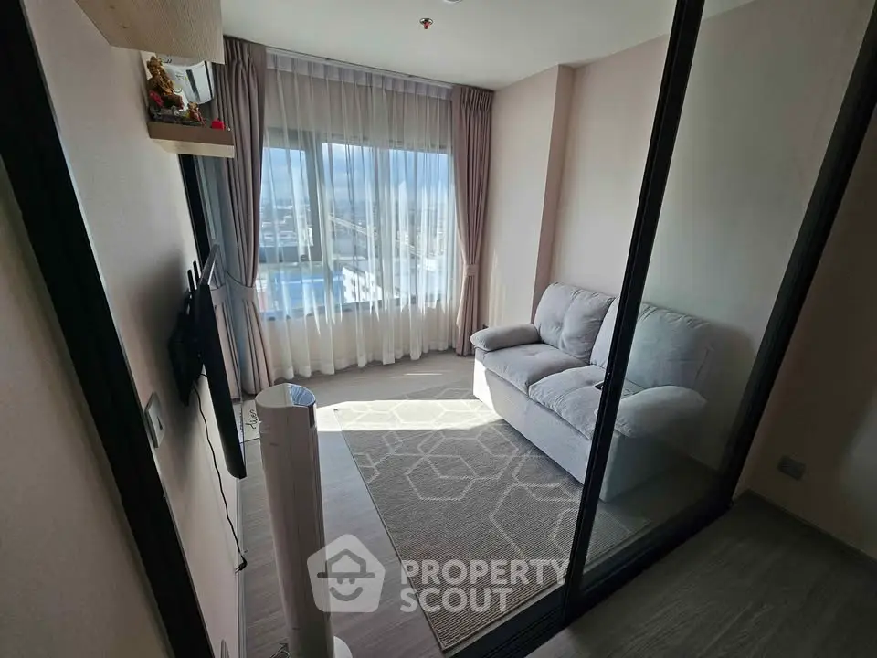 Modern living room with glass partition and cozy sofa, featuring a large window with city view.