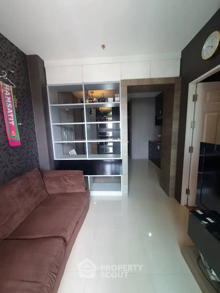 Modern living room with sleek shelving and cozy brown sofa in stylish apartment.