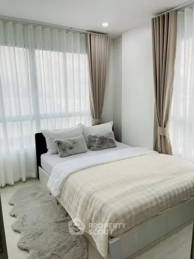 Cozy bedroom with elegant curtains and plush bedding in a modern apartment.