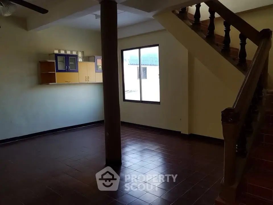 Spacious living room with staircase and large window, ideal for family gatherings.