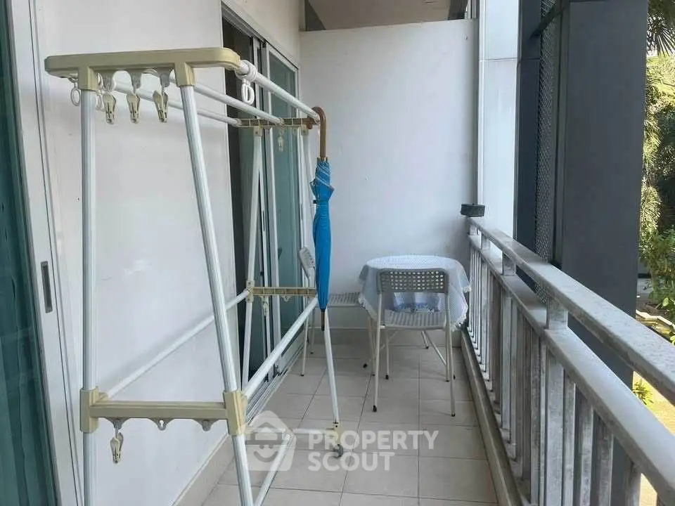 Spacious balcony with seating area and drying rack, perfect for relaxation and utility.