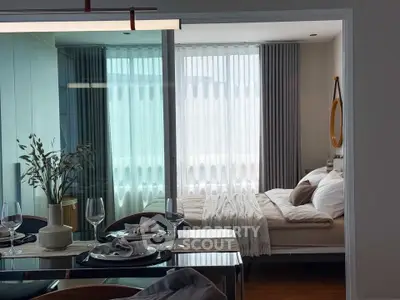 Modern open-plan living and bedroom area with elegant dining setup and cozy bed.