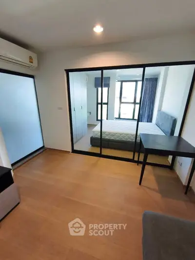 Modern bedroom with glass partition and wooden flooring in a stylish apartment.