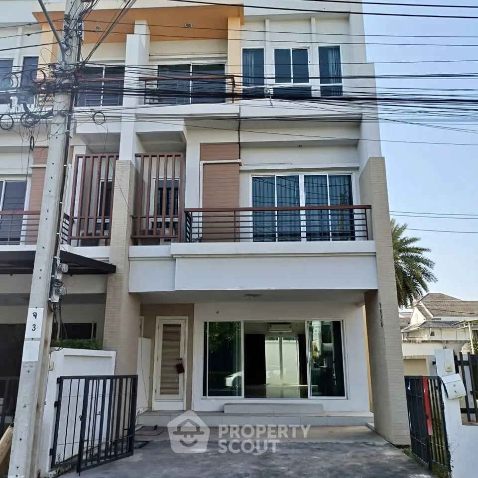 Modern three-story townhouse with sleek design and large windows in a suburban neighborhood.