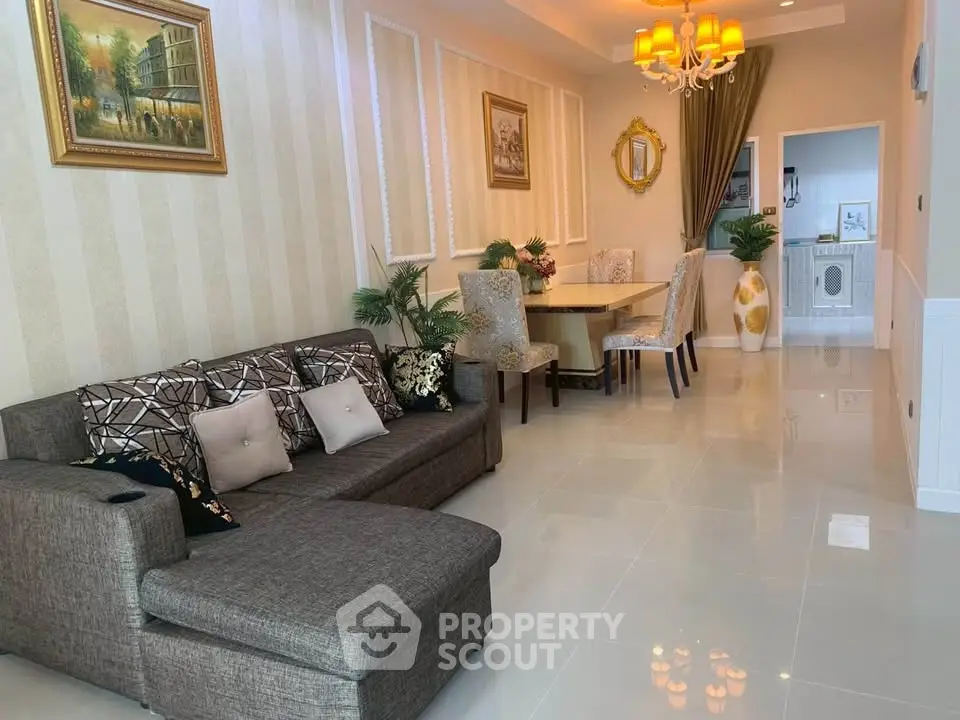 Elegant living room with stylish decor and dining area, featuring a cozy sofa and modern chandelier.