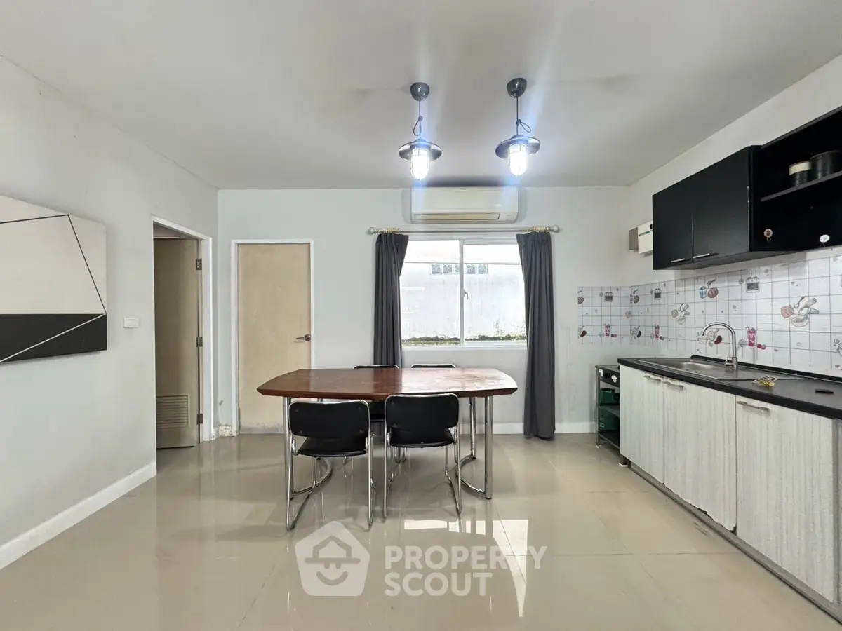 Spacious kitchen with modern fixtures and dining area, featuring sleek cabinetry and stylish lighting.