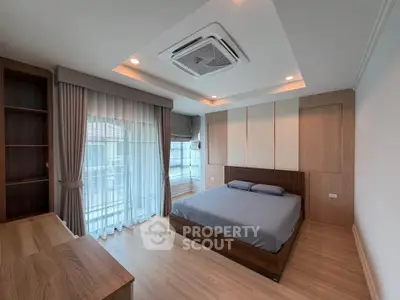 Spacious modern bedroom with large windows and elegant wooden furnishings